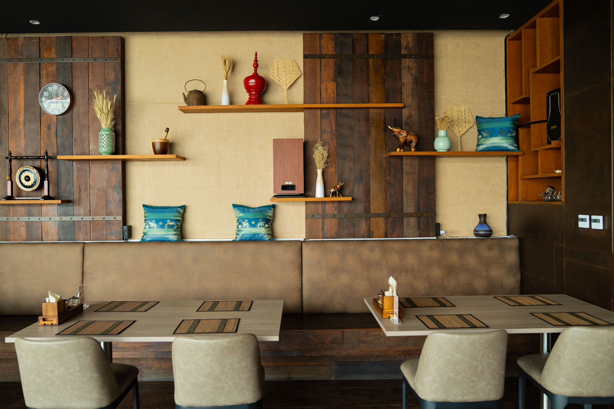 Tai Yai Noodle dining room — wooden walls, Shan textile cushions, brass elephants and lacquerware on the shelves